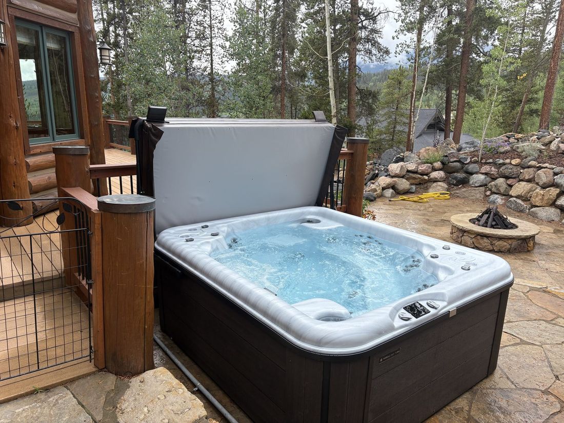 Freshly serviced hot tub on a mountain patio with fire pit and forest view — guest ready